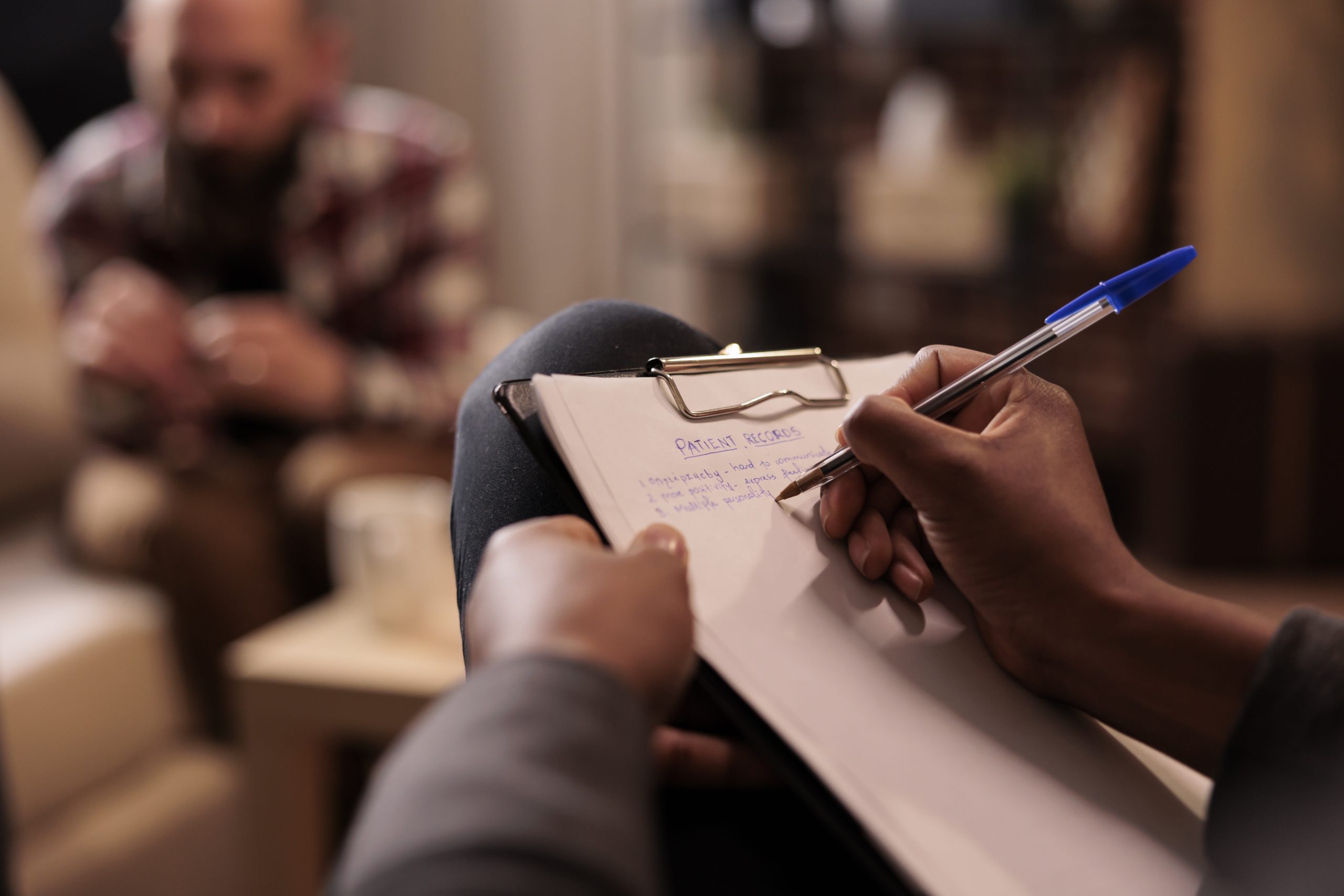 Male psychologist taking notes at couple therapy session to help with relationship issues, counselor giving advice. Explaining marriage problems, using paper to do psychoanalysis. Close up,